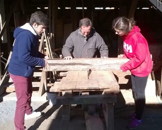 Pablo el P. Javier y Amanda cortando madera para hacer bancos en un comedor social.