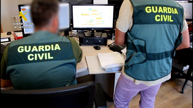 Pareja de guardias civiles con ordenador, estafa informática mediante SMS